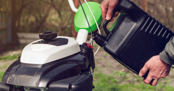 A man pours gasoline from the canister into the cultivator tank.