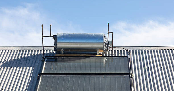 Rooftop solar hot water cylinder with photovoltaic cells  on rural house converting the renewable sustainable energy of the sun for electricity and heating