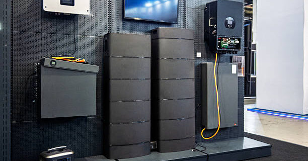 This detailed display showcases a comprehensive modern home energy storage system, featuring a range of essential components for sustainable power management. prominently displayed are several advanced inverters, including both wall-mounted and an open-faced unit revealing its internal circuitry, alongside sleek, tall battery storage units designed for residential or commercial applications. A smaller wall-mounted battery pack and a versatile portable power station complete the setup, highlighting various options for energy independence and backup power. The arrangement emphasizes innovation in renewable energy integration and efficient power distribution, making it ideal for demonstrating cutting-edge smart home or off-grid solutions.