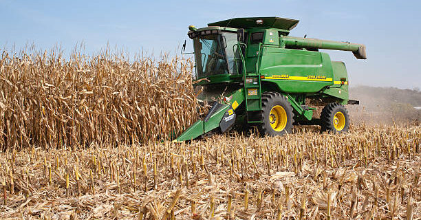 "West Albany, Minnesota, USA - October 12, 2010: A farmer harvests corn in a John Deere combine. John Deere is a major manufacturer of agricultural machinery."